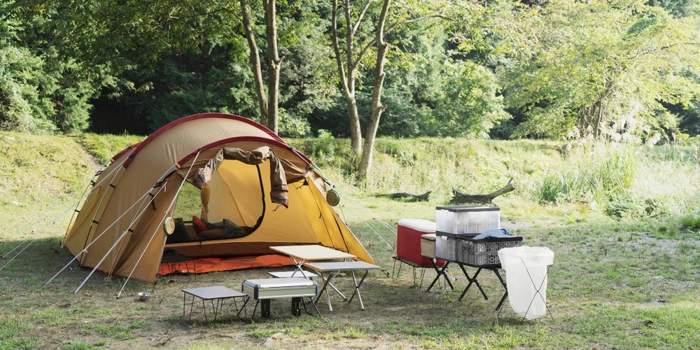 A camp site complete with cooler, portable tables and chairs, and more