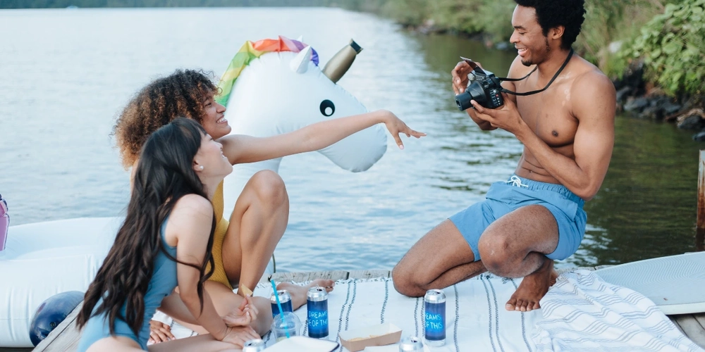 Man taking pictures of his friends during a swim party at the lake