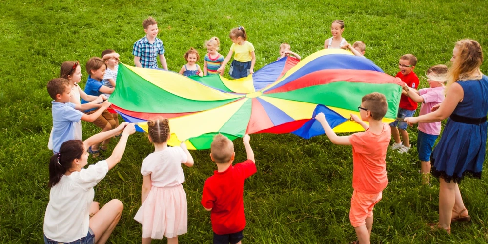 Several kids playing with a colorful parachute on campgrounds