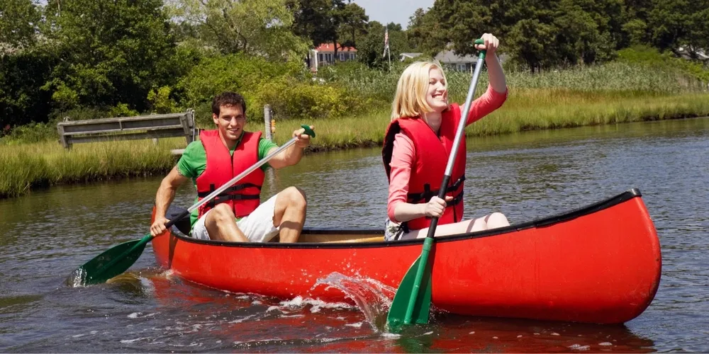 Tent campers doing water activities, on a canoe on a lake