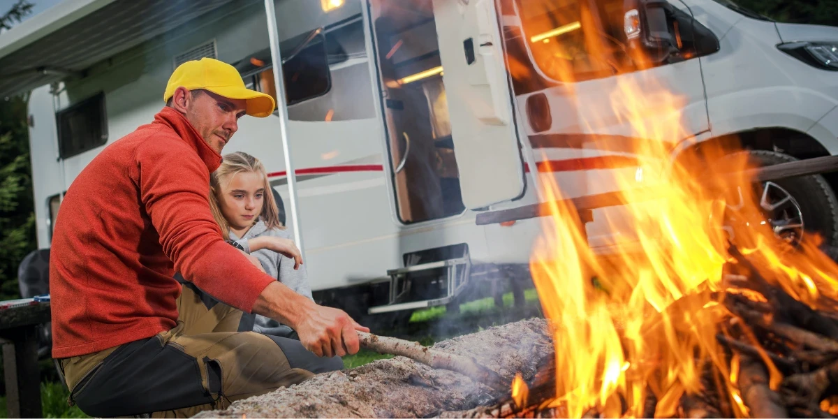 Father and daughter tending the campfire next on their RV park pitch