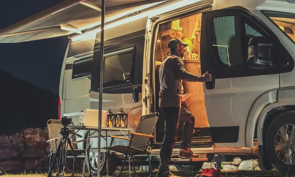 Man at the door of his camper van in the early hours of the evening