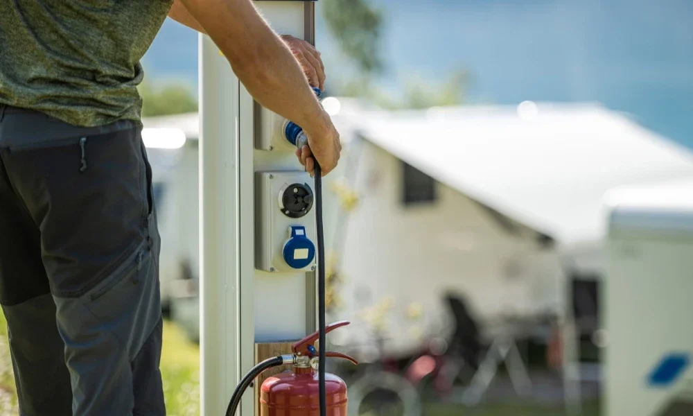 Man attaching camping RV cable to electric post.