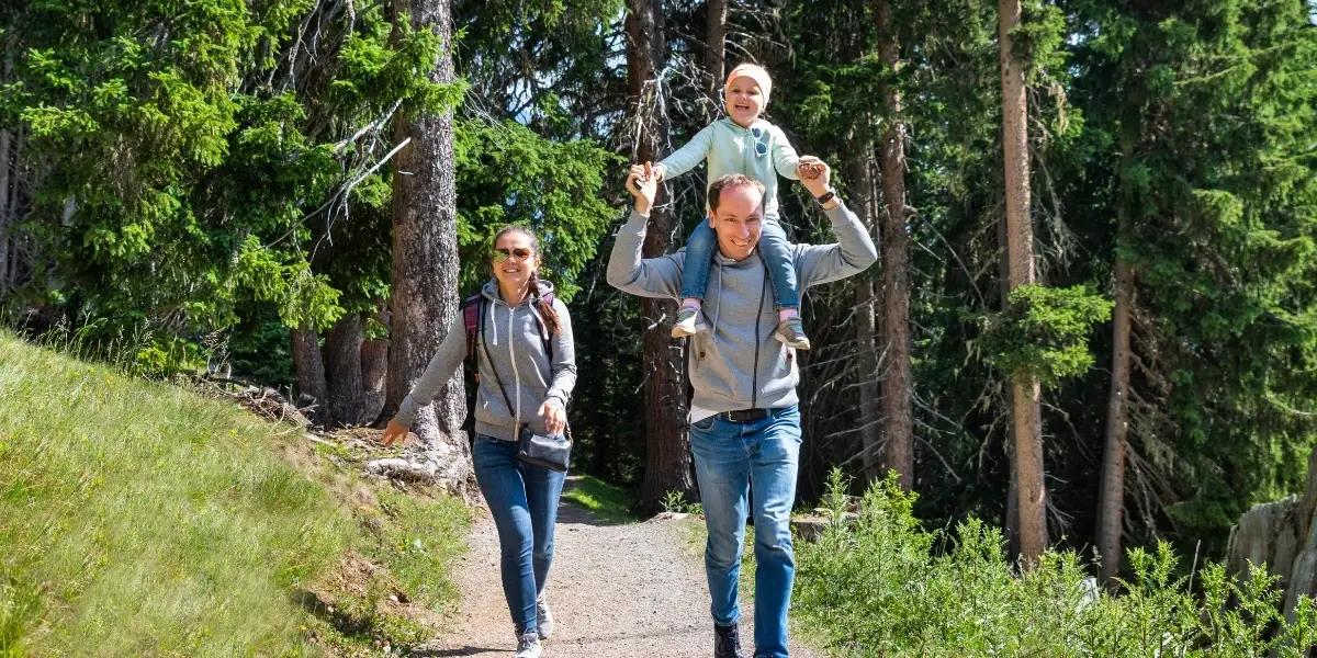 Woman, man, and baby on man's shoulders on a walking trail