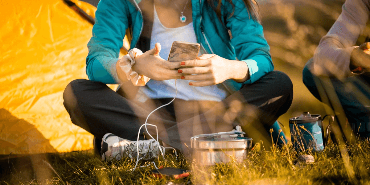 photo of a woman using her phone in front of her tent