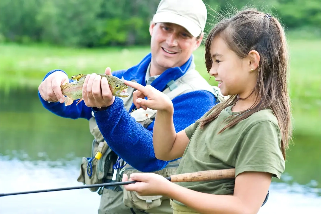 An image of a man and a girl catching a fish.