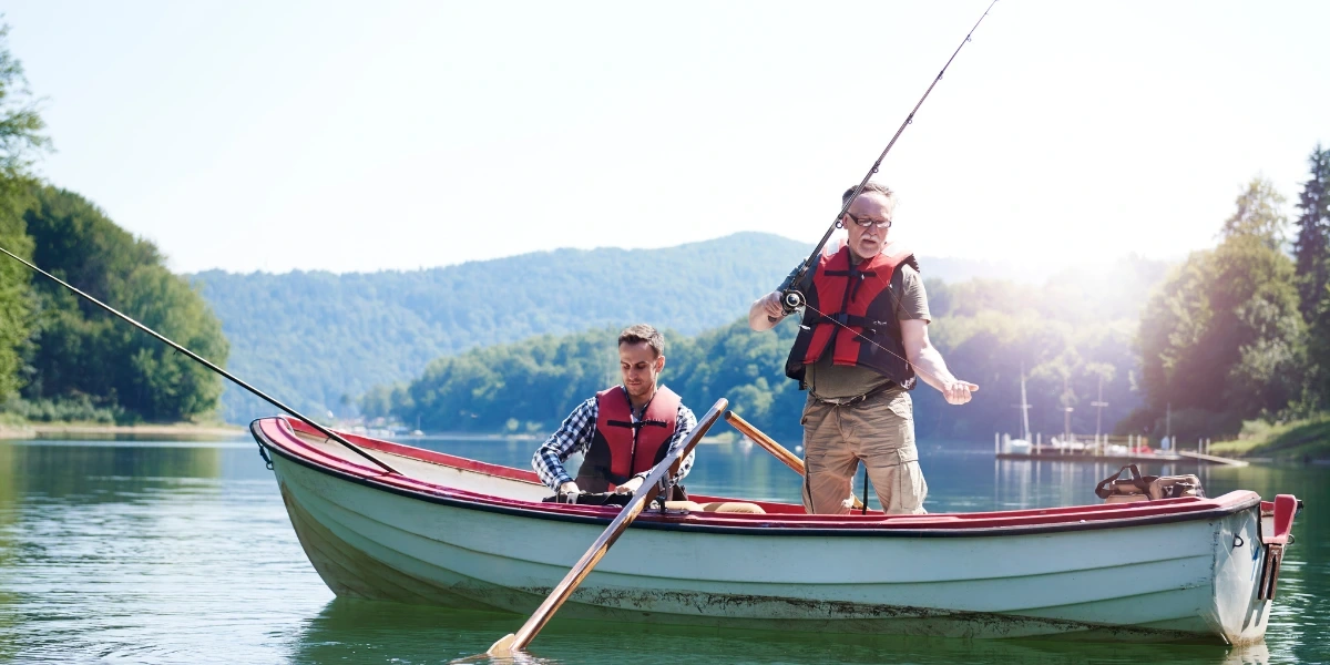 An older man and his son fishing in a lake during peak season