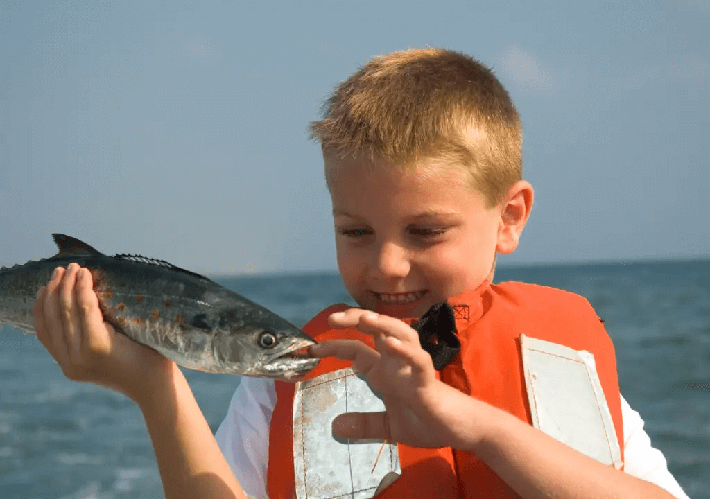 An image of a boy holding a fish he caught.